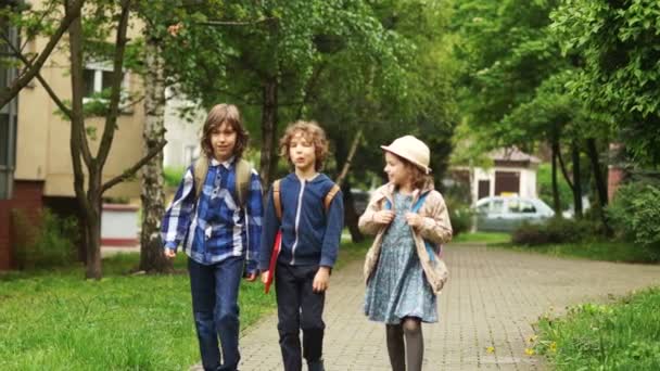 Bir kız kardeşi ve iki kardeş okuldan döndürür. Çocuklar onların sırt çantası taşımak ve birbirleri ile iyi eğlenceler. Çocuk dostluk — Stok video