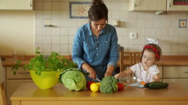 Mladá matka se připravuje večeře v kuchyni. Pořezala se mrkev. Malá dcera pomáhá moje matka. Holky už pečete. Rodinná večeře — Stock video