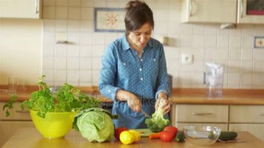 Mutfakta esmer brokoli yıkılıyor. Kız dans ediyor ve müzik şarkı söylüyor. Ev mutfak