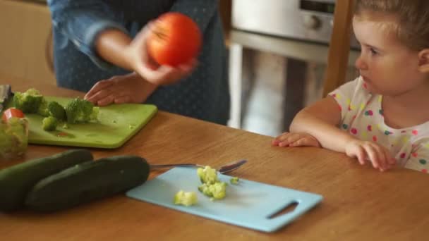 A mãe dá um tomate à filha, limão. A rapariga afasta os vegetais. Comida de bebé. Estilo de vida saudável. Caprichos infantis . — Vídeo de Stock