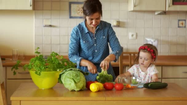 Una piccola risata aiuta sua madre a cucinare. Hanno tagliato i broccoli. Zuppa vegetariana. Uno stile di vita sano. Famiglia vegetariana. Dieta sana. Genitorialità. HD — Video Stock