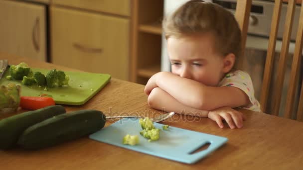 Klein meisje in de keuken. Ze is boos, huilen, haar gezicht te verbergen. Niet hongerig. Weigert te eten. Kinderachtig grillen. — Stockvideo