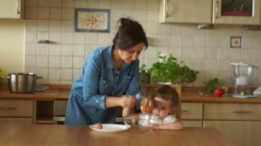 Bebek anne mutfakta yardımcı olur. Kızlar bir cam kaseye yumurta kırmak. Anneler Yardımcısı.