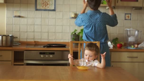 Mi hija ayuda a su madre a cocinar huevos revueltos. Asistente de mamás. Desayuno familiar . — Vídeos de Stock