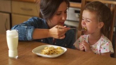 Güzel bir esmer kızı besleniyor. Gıda darbeler ve kız için verir. Bebek maması, sağlıklı iştah. Mutlu bir aile