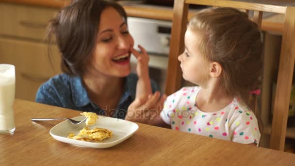 Mãe e filha felizes limpam os lábios após o kefir, rindo alegremente . — Vídeo de Stock