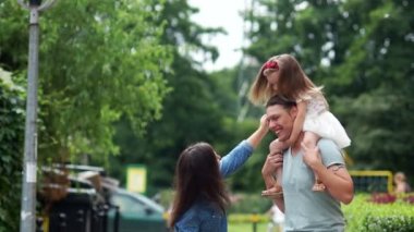 Mutlu bir aile. Babası kızını onun omuzlarında duruyor. Anne kıza doğru yatırır ve mutlu bir şekilde gülüyorlar. Güzel rüzgarda çırpınan saç.