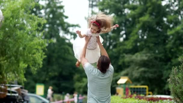 Der glückliche Vater wirft seine Tochter hin. das Mädchen lacht fröhlich. — Stockvideo
