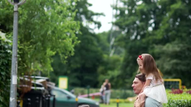 Uma família jovem feliz, mãe, pai e filha se divertem no parque. Fins de semana, férias em família . — Vídeo de Stock