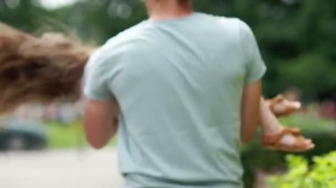 Mutlu baba kızı kucağında dönüyor. Kız başında, uzun saçları rüzgarda çırpınan kırmızı bir çelenk yaptı.