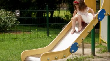 Açık havada oynamak sevimli küçük kız portresi yaz güneşli gün boyunca parkta çocuk slayt.