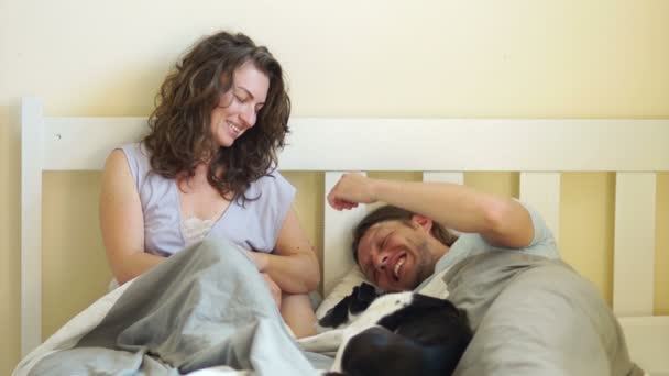 Mladý dospělý pár v posteli hrát se svým psem — Stock video