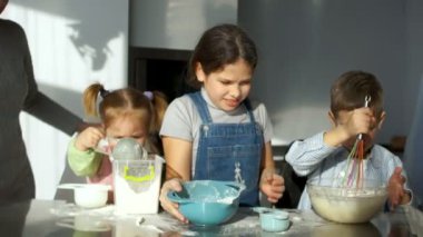 İki kız kardeş 2 ve 9 yaşında ve 6 yaşındaki kardeşi mutfakta hamur yoğurmak. Anne onlara yardımcı olur. Çocuk pişirme için hamur yapmak