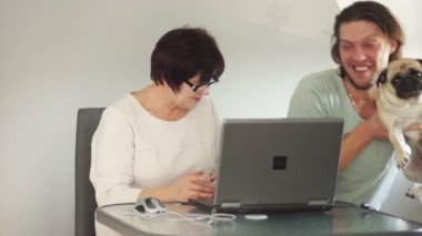 Anne ve oğlu Skype'ta kullanarak akrabalarıyla. Seslenmek belgili tanımlık köpek ve kameraya göster. Şaka yollu sallanan köpek pençe