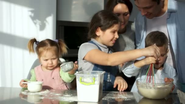 eine glückliche Familie von fünf Köchen in der Küche. Kinder spielen mit Mehl, Mama lacht. verlangsamte Bewegung