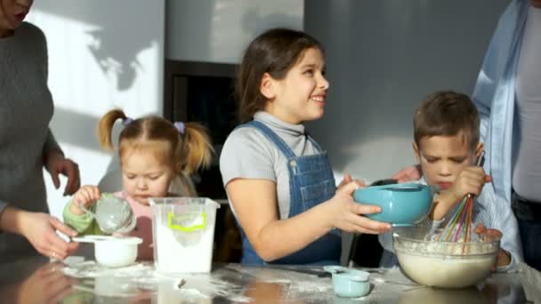 Cała rodzina w kuchni przygotowuje się żywność. Najstarsza córka barwione jej ojca z mąki. Żart dla dzieci. Troje dzieci — Wideo stockowe