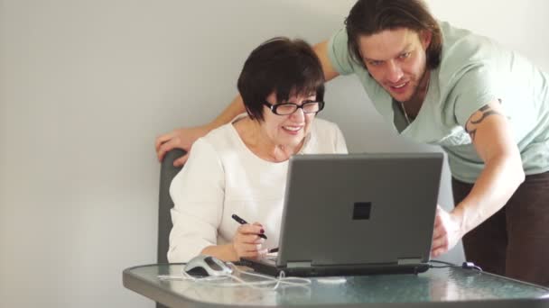 Colegas trabajando juntos en una computadora en su oficina. Se ríen sinceramente. Mujer haciendo gesto de mano — Vídeo de stock