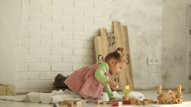 Een prachtige baby speelt op de verdieping met houten kubussen. Educatief speelgoed. Voorschoolse educatie. Kleuterschool — Stockvideo