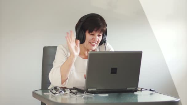 A middle-aged woman communicates with her family via Skype. Video connection. Waving his hand, says goodbye, ends the conversation — Stock Video