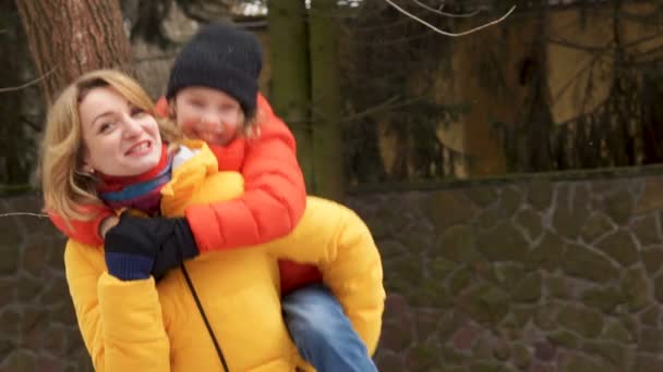 Glückliche Mutter und Sohn auf einem Spaziergang. der Junge sitzt auf Mutters Schultern, sie lachen und lachen glücklich — Stockvideo