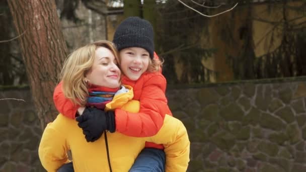 Happy mother and son on a walk. The boy is sitting on Moms shoulders, they laugh and laugh happily — Stock Video