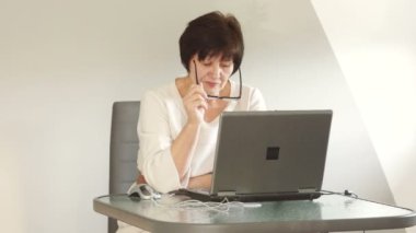 Laptop ile çalışan Olgun kadın. O iş kıyafeti ve katı gözlük giymiş