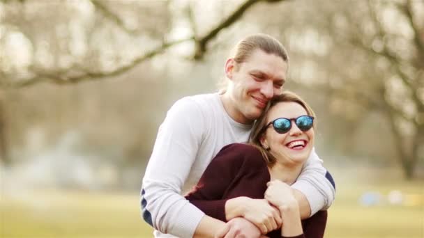 Счастливая любящая пара на отдыхе в весеннем городском парке на фоне голых деревьев — стоковое видео