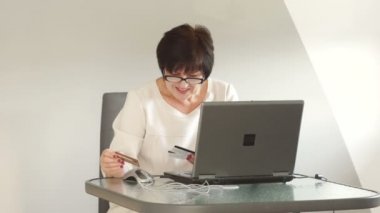 Orta yaşlı bir kadın onu rapor tidies. Uzaktan bankacılık, çevrimiçi bankacılık