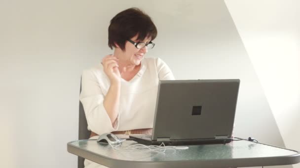 Mujer de negocios en la oficina en el trabajo. Mira cuidadosamente la pantalla del portátil sobre las gafas. Sonriente dama de negocios — Vídeos de Stock