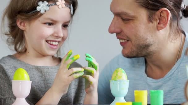 Apa és lánya az festeni a húsvéti tojás. A lány apja festékkel piszkos. Nevetnek, szórakozás — Stock videók