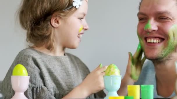 Frohe Ostern. Vater und Tochter bemalen sich gegenseitig Eier und Gesichter. Familienwitze — Stockvideo