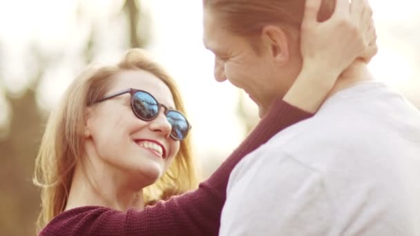 Retrato cerrado de una pareja enamorada. Un hombre y una mujer se abrazan y se miran en los rayos del sol poniente — Vídeos de Stock