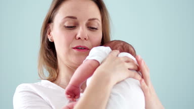 Annesi şefkatle gülümsüyor ve yeni doğan bebeğin omzuna yatıyor. Yeni doğan sağlığı, püskürtme. Neonatologist. Anneler günü.