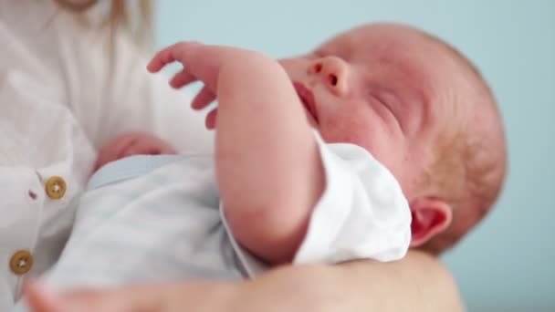 Portret van een pasgeboren baby. Hij slaapt met zijn moeder in zijn armen en de handgreep beweegt in zijn slaap. Childrens dag. — Stockvideo