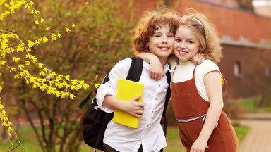 Okul, erkek kardeşi ve kız kardeşi, erkek ve kız bir çiçek açması ağaç bahar arka planı sarıl. Bilgi günü. Okula dönüş. Okul dostluk