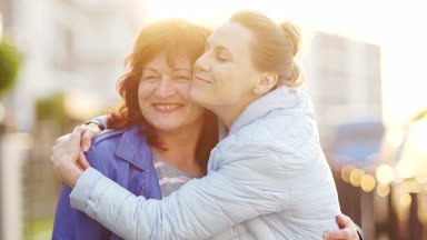 Olgun anne ve yetişkin bir kızı üstünde belgili tanımlık sokak ve kucaklamak araya geldi. Nesillerin mutlu aile, süreklilik. Anneler günü
