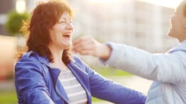 Anne ve kızı sokakta sarılıyorlar. Bahar ceketler giyindin. Gün batımı. Anneler günü. Beklenmeyen Toplantı