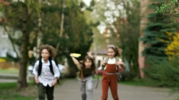 Kinder, Jungen und Mädchen laufen von der Schule und winken mit Rucksäcken. Urlaub zum Vergnügen. zurück zur Schule. Kindertag — Stockvideo