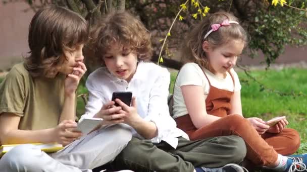 Gli scolari giocano con gli smartphone durante le vacanze scolastiche. Dipendenza da gioco. Problemi di educazione dei bambini. Caratteristiche psicologiche dei bambini adolescenti — Video Stock