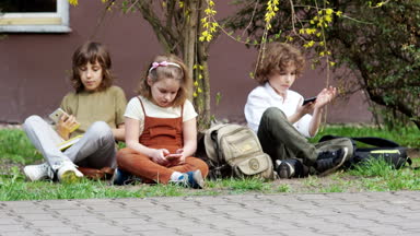 Okul çocukları akıllı telefonlar üzerinde oyun. Okul değişikliği bitti. Çocuklar onların çanta dolu ve okula gittim. Okula dönüş