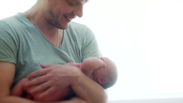 Een jonge vader kalmeert een huilende pasgeboren baby. De naakte kind is in de handen van een atletische man. Fathers Day. Childrens dag — Stockvideo