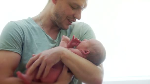 El padre calma al recién nacido. Se acuna y lo sostiene en sus brazos. El niño tiene hambre, quiere comer, toma una mano en su boca. Lactancia materna — Vídeo de stock