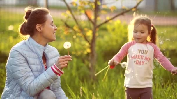 Glückliche Mutter und Tochter, die auf Löwenzahn blasen. Frühjahrspause. Muttertag. Familientag — Stockvideo