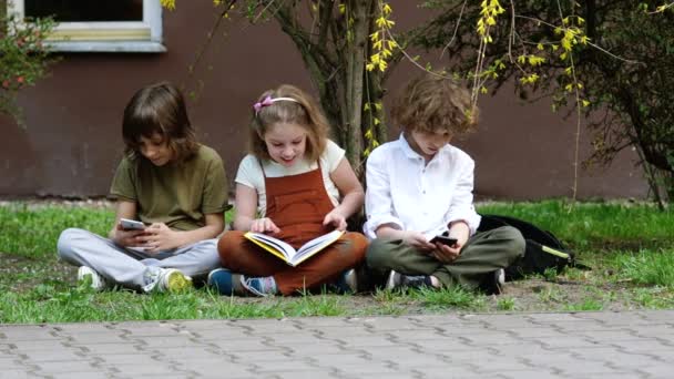 Das Mädchen will das Buch lesen. Jungen sind mit ihren Smartphones beschäftigt. Ein Schüler macht ein Selfie. Internetsucht. Zurück zur Schule — Stockvideo
