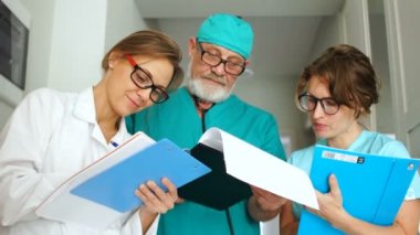 Genç bir cerrah ve iki asistanının yakın portresi. Klinik sağlık personeli iş başında. Tıp ve sağlık hizmetleri kavramı