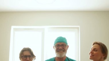 Bir grup profesyonel doktor, olgun bir adam ve iki genç kadın. Klinikteki doktorların yakın portresi.