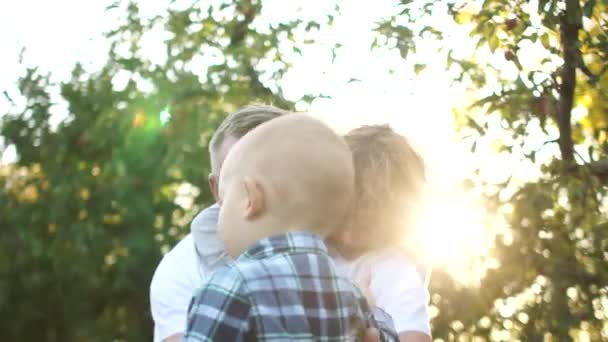 Grandfather with a beard and glasses have fun in the apple orchard with his two grandchildren. Happy family, two generations — Stock Video