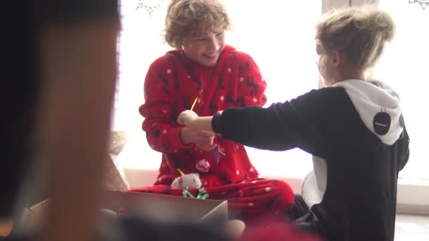 Los niños rizados, un niño y una niña sacan pelotas de juguetes de Navidad y una estrella de la caja. Preparativos de Navidad — Vídeos de Stock