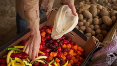 Kadın eli, tekrar kullanılabilir bir kumaş torbasından acı biber toplar. Pazardan alışveriş, ekolojik ambalaj