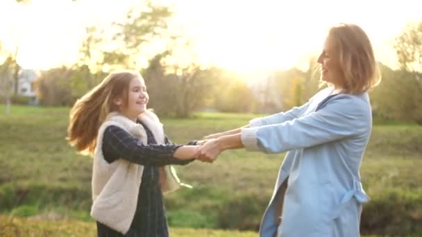 Madre e hija se divierten en el parque de otoño. Una niña y su joven madre giran cogidas de la mano. Día de las Madres — Vídeos de Stock